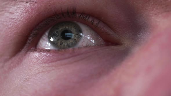 Reflection of screen on person's blue green eye in dark room 3