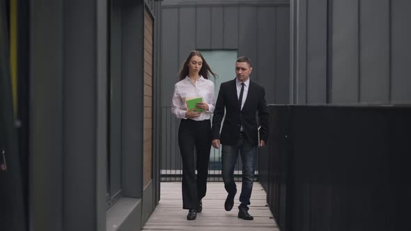 Wide Shot Serious Caucasian Man and Woman Walking for a Meeting Talking Outdoors