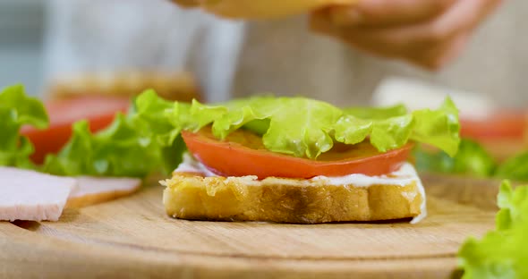 Female Chef in the Kitchen of the House Collects a Sandwich