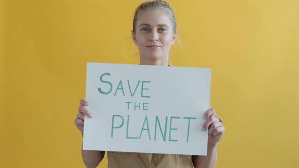 Slow Motion of Blond Girl Holding Save Planet Sign on Yellow Background