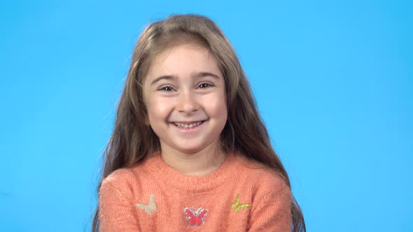 Child Is Looking at the Camera and Smiling, Blue Background.