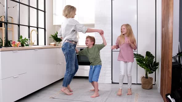 Excited Mom or Babysiter and Two Kids Boy and Girl Jumping Dancing Laughing in Modern Scandinavian