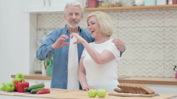 Loving Old Couple Smiling at Camera in Kitchen