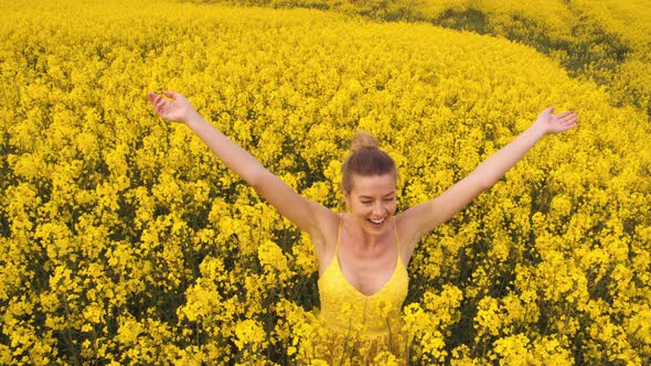 Woman Standing in the Middle of the Canola Flowering Fields 