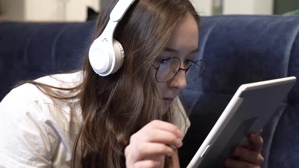 A Girl at Home with a Tablet on Her Headphones