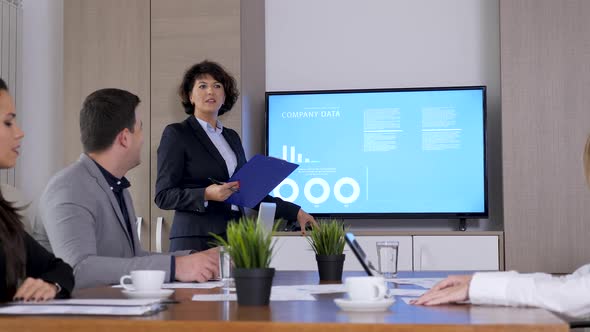 Businesswoman in Meeting Room in Front of Big Screen TV