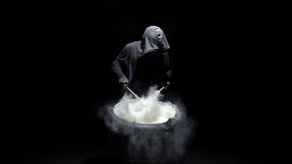 Hooded Man Beats Drum with Flour