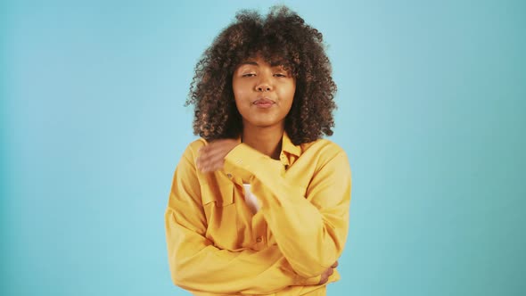 Young Afro American Female Sending you an Air Kiss Flirting and Smiling While Posing Against Blue