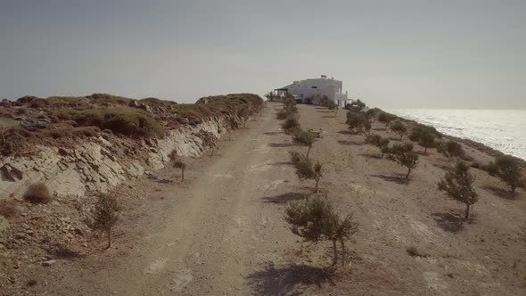 Aerial view of a dirt road with a big house on the sea, Greece.