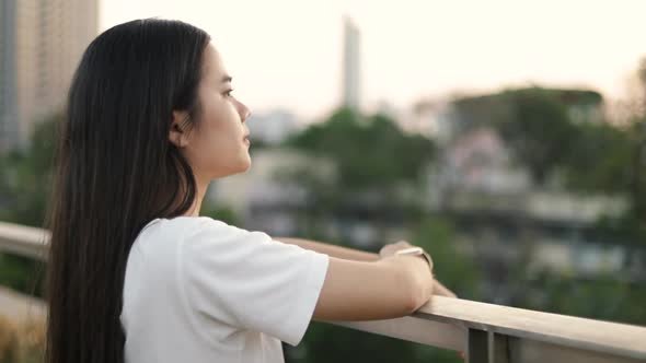 Asian woman enjoying peaceful sunset and exhaling fresh air relaxing outdoors.