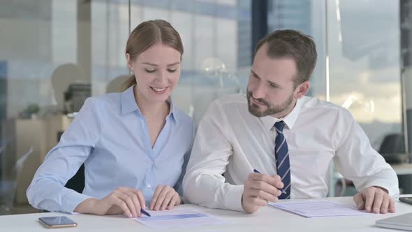 Executive Business People Discussing and Reading Documents in Office