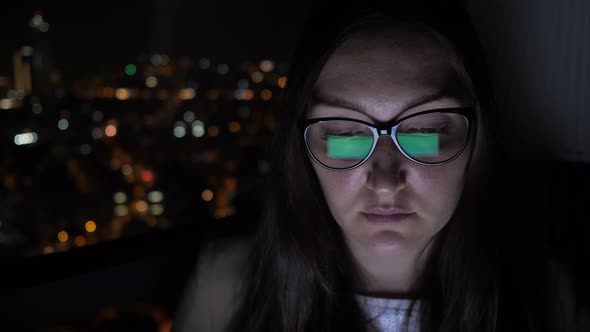 Portrait of Woman in Glasses Working on Computer Near the Window with Cityscape.