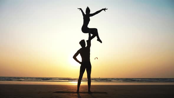 Fit Sporty Couple Practicing Acro Yoga with Partner Together on the Sandy Beach.