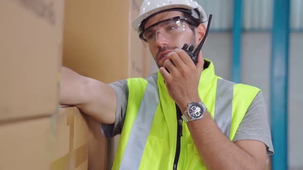 Professional Cargo Worker Talks on Portable Radio to Contact Another Worker