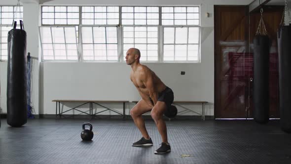 Fit caucasian man working out with kettle bell at the gym