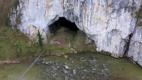 Aerial View of a Big Cave Entrance and Wild Mountain River