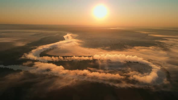 Aerial drone view of nature of Moldova at sunset. River and lush fog above it, village, greenery
