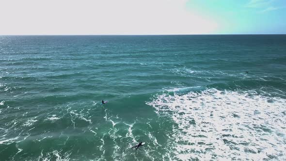 Surfers bobbing on top of breaking clear waves