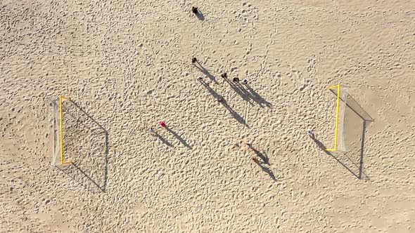 AERIAL: Two Teams Plays Football on a Sandy Beach on Beautiful Summer Day