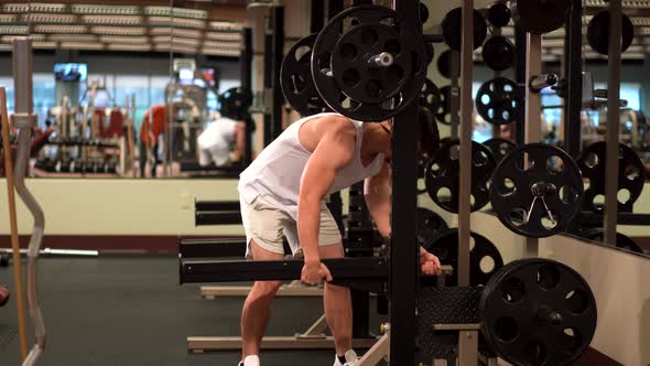 Bodybuilder adjusting barbell weight safety support for squats