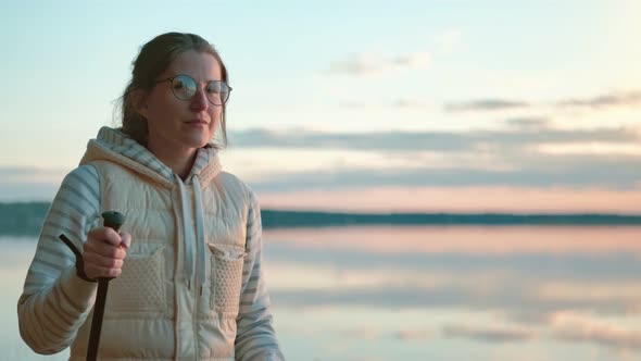 Woman Practicing Nordic Walk Near Pond at Sunset Steadicam Establish Shot