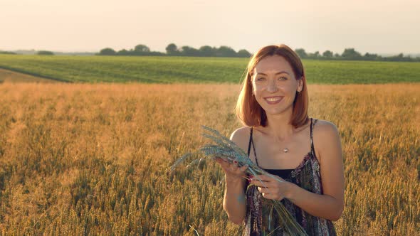 Portrait of a Woman Artist Who Shows Emotions and Smiles. Woman Holds in Her Hands Ears of Wheat