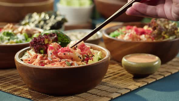 Eating Poke Bowl Closeup Taking Shrimp with Chopsticks Dipping Into Sauce