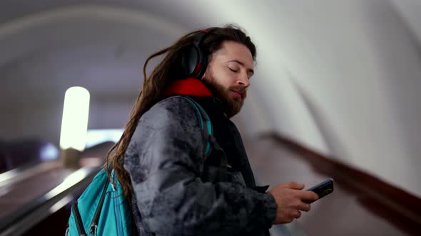 Stylish Young Man is Moving Up on Escalator in Underground Using Smartphone