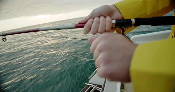 Fisherman's Hands Hold a Fishing Rod While Fishing in the Ocean