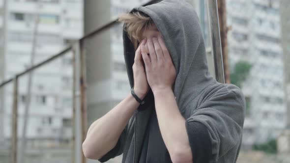 Frustrated Caucasian Young Man Holding Head with Hands. Portrait of Depressed Handsome Guy Standing