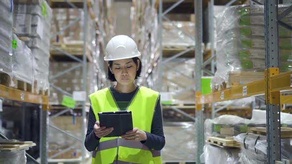 Young Female Employee Walking on Storehouse Room and Using Tablet While Working.