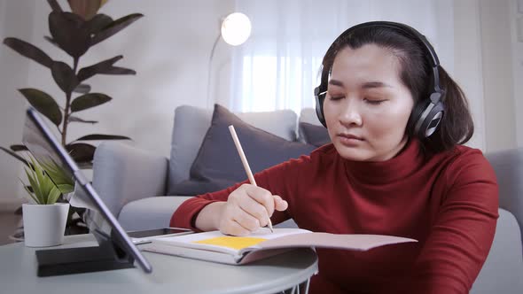 Businesswoman redshirt using a tablet with headphone for meeting online at home