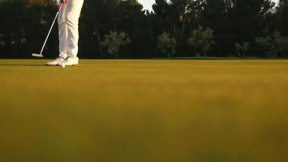 Golfer striking a ball during sunset
