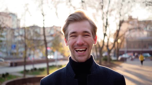 Portrait. Happy European Man Laughs Funny in Urban Sunset Background. Emotional