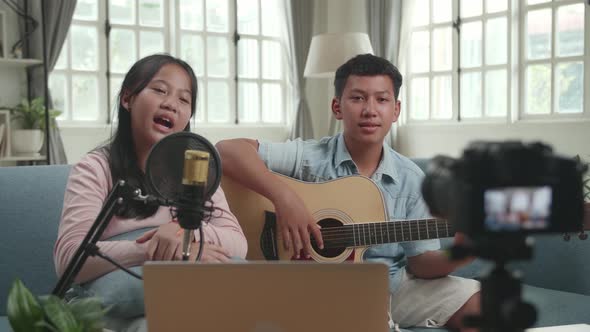 Asian Boy With Guitar And Girl Talking To Camera While Live Streaming