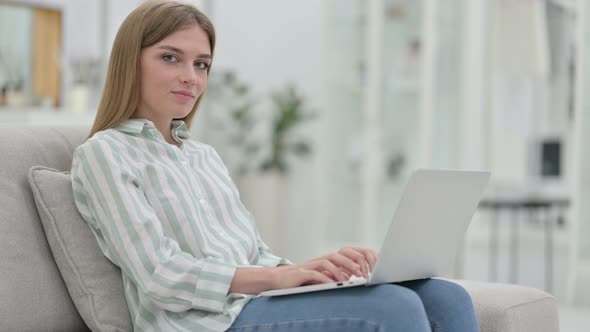 Young Young Woman with Laptop Smiling at Camera at Home 