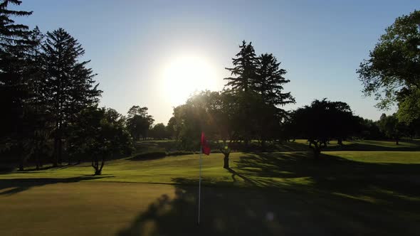 Rising Shot of Golf Flag Silhouette During Sunset with Lens Flare, Realtime Drone Shot