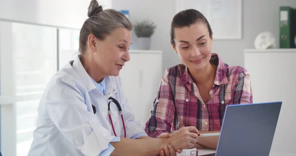 Doctor Consulting Patient in Clinic Office Presenting Results on Laptop Computer