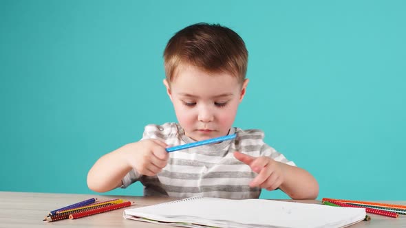 Young Talented Boy Draws a Pencil Drawing in Album on Blue Background.