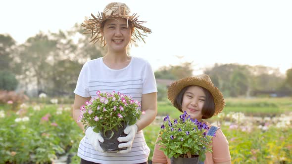 Slow motion Happy Asian mother and daughter planting flower together in the garden.