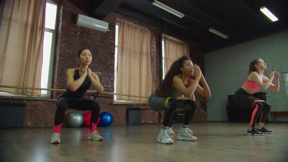 Diverse Fit Women Doing Squats with Resistance Band