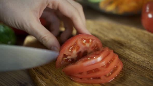 Close Up Shot of Woman Hands Slicing Tomato on Wooden Cutting Board for Salad on the Table