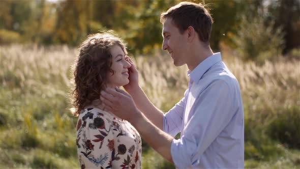 Positive Young Happy Loving Couple Walking on Meadow in Summer Holding Hands.