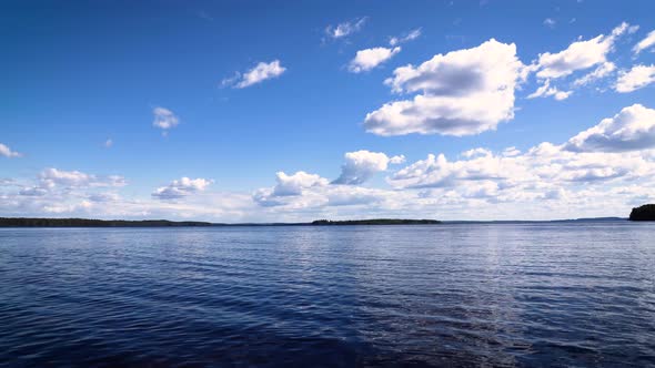 time lapse of the water on a lake in finland with white clouds sliding past and a boat passing by in