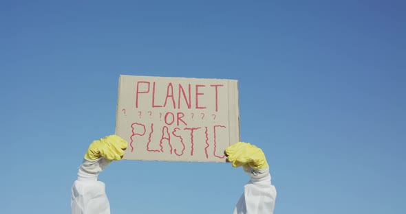 Protest Sign "Planet or Plastic" on Blue Sky Background Raised By Hands