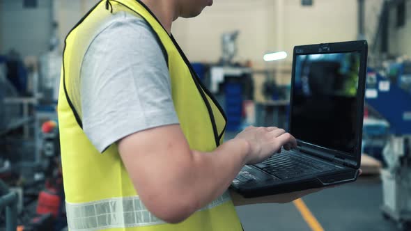 Industrial Engineer with Hard Hat Working with Laptop at Factory