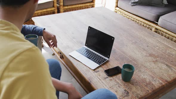 Father and son having coffee during video call on laptop with black screen and copy space