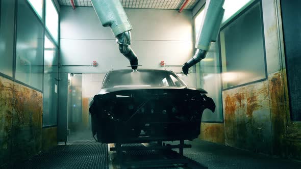 Robotic Arms Spray Painting a Vehicle Body at a Car Manufacturing Plant