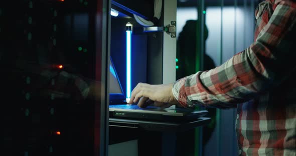 Crop Man Working on Laptop in Server Room