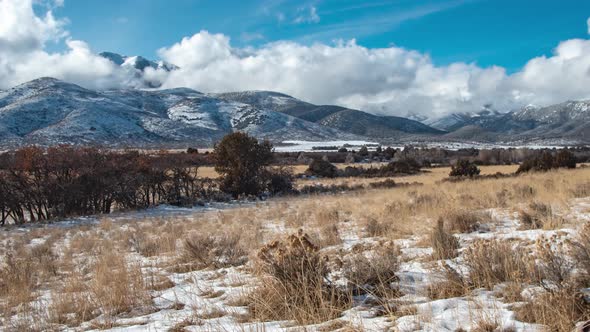 Panning time lapse of snowy mountains and cloudscape with the clouds forming and reacting to the mou